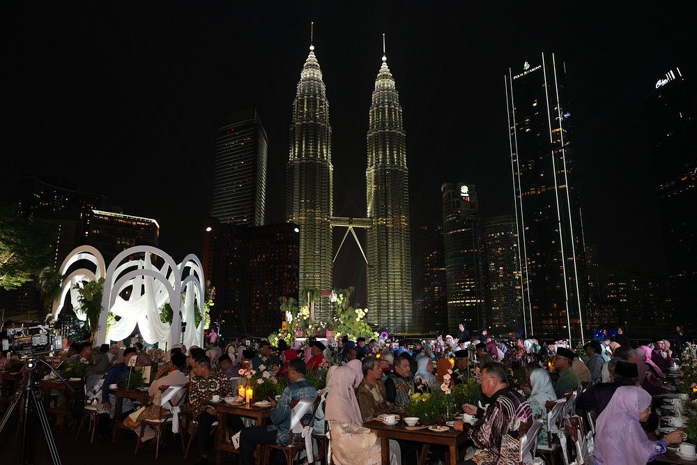 Large evening event dinner on the terrace with guests seated beneath the lit Petronas Towers