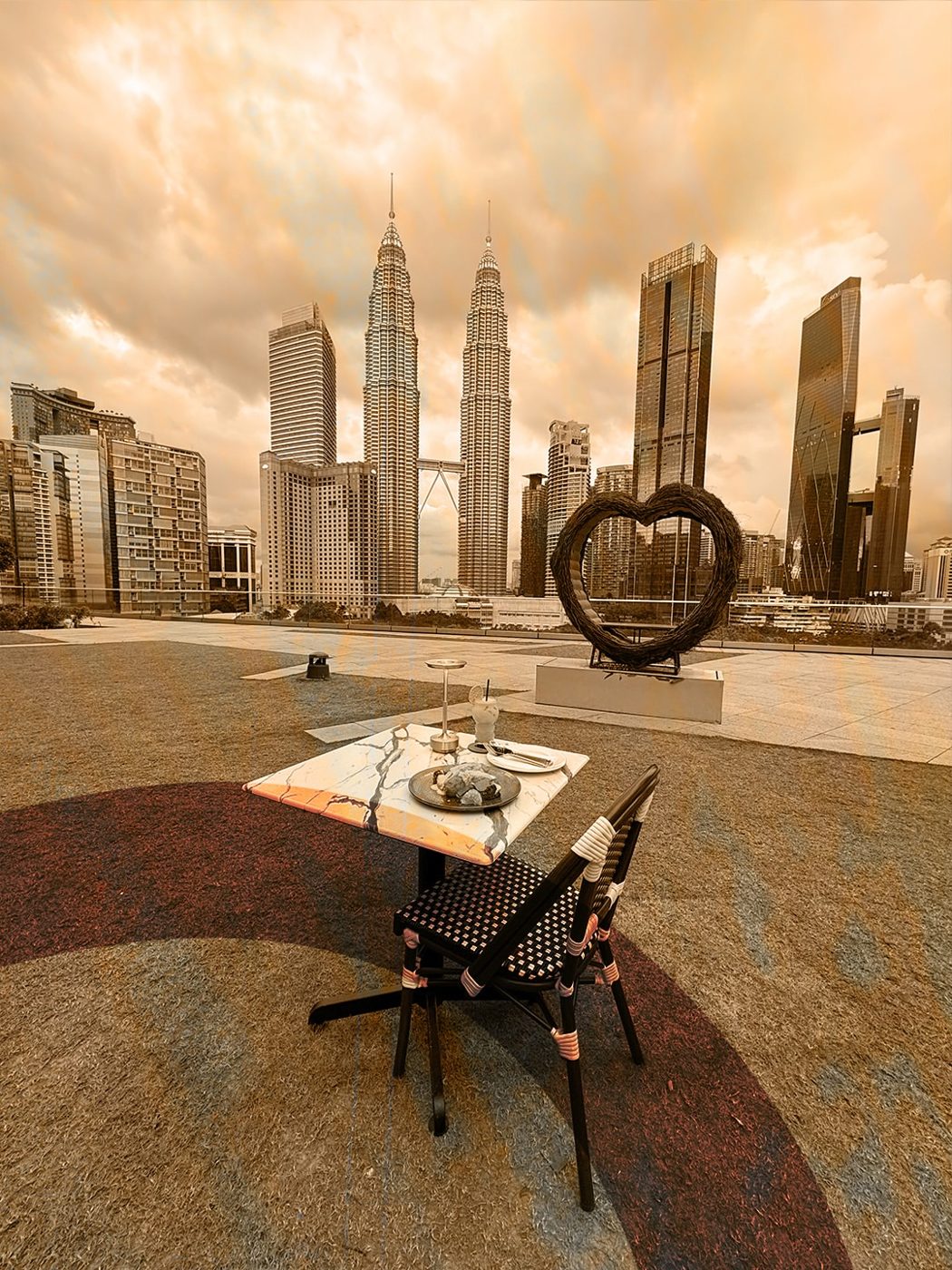 Sepia-toned rooftop table at Anjum KLCC with a heart sculpture and the Petronas Towers behind