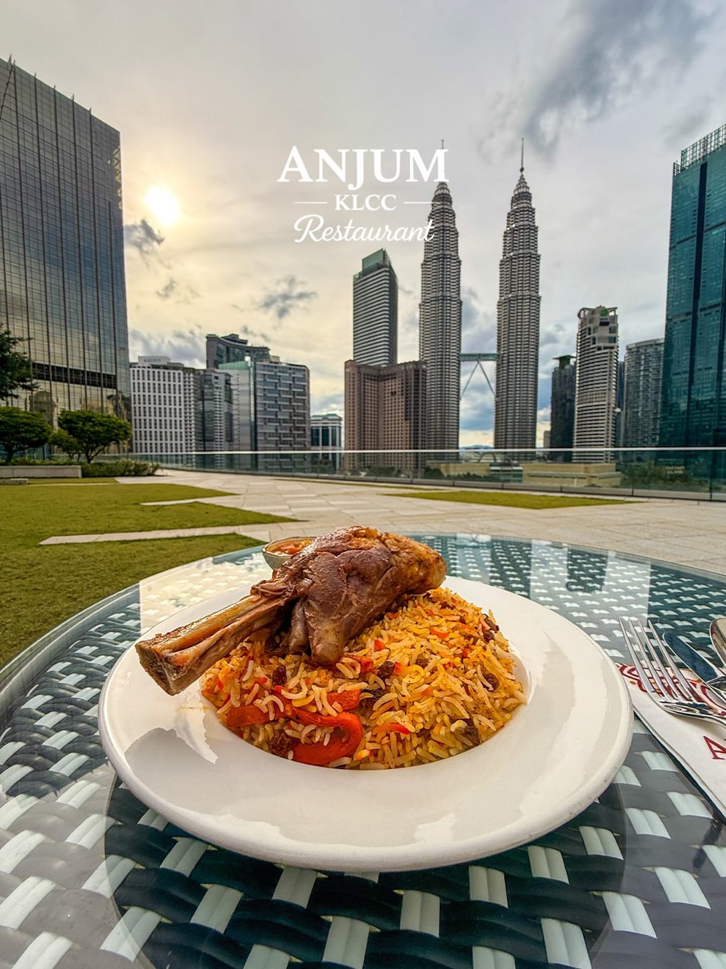 Slow-cooked lamb shank served over spiced rice with the KLCC skyline in the background